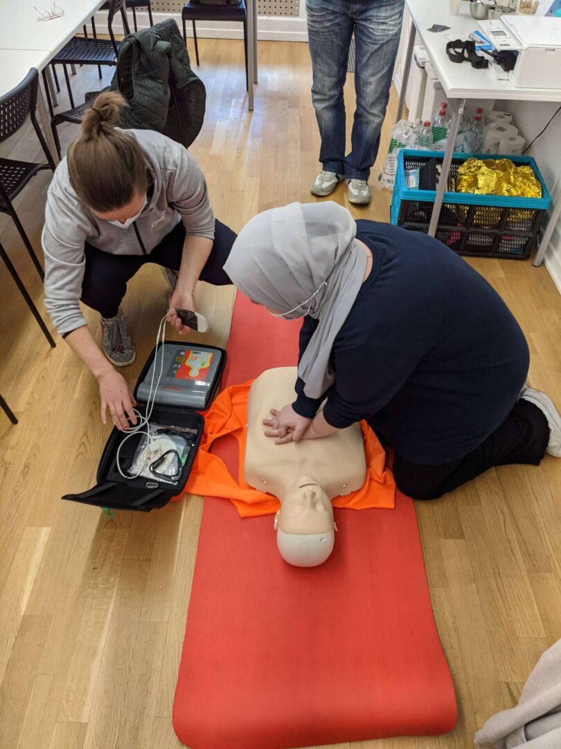 Two people practicing cpr on a dummy.