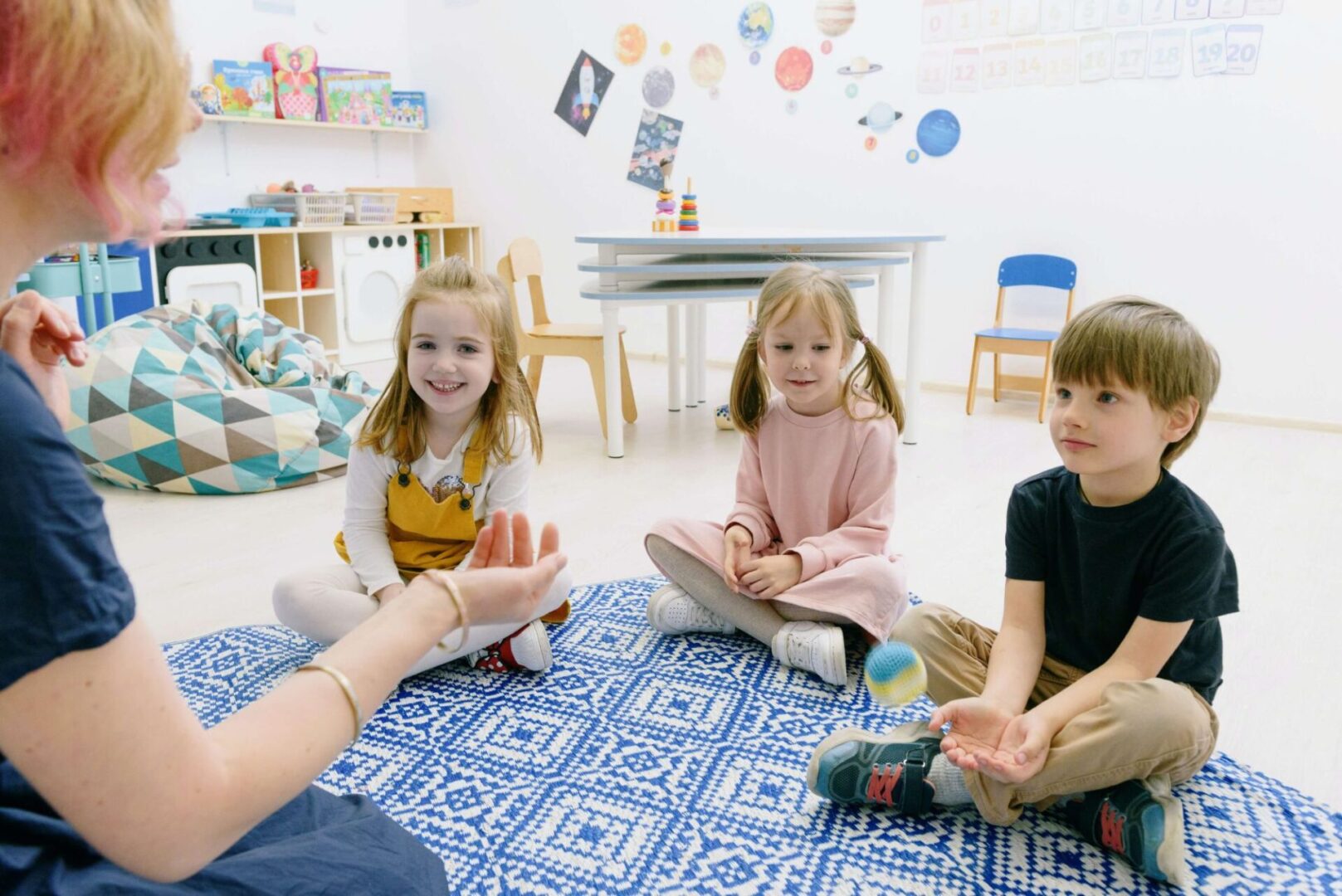 A group of children sitting on the floor in front of an adult.