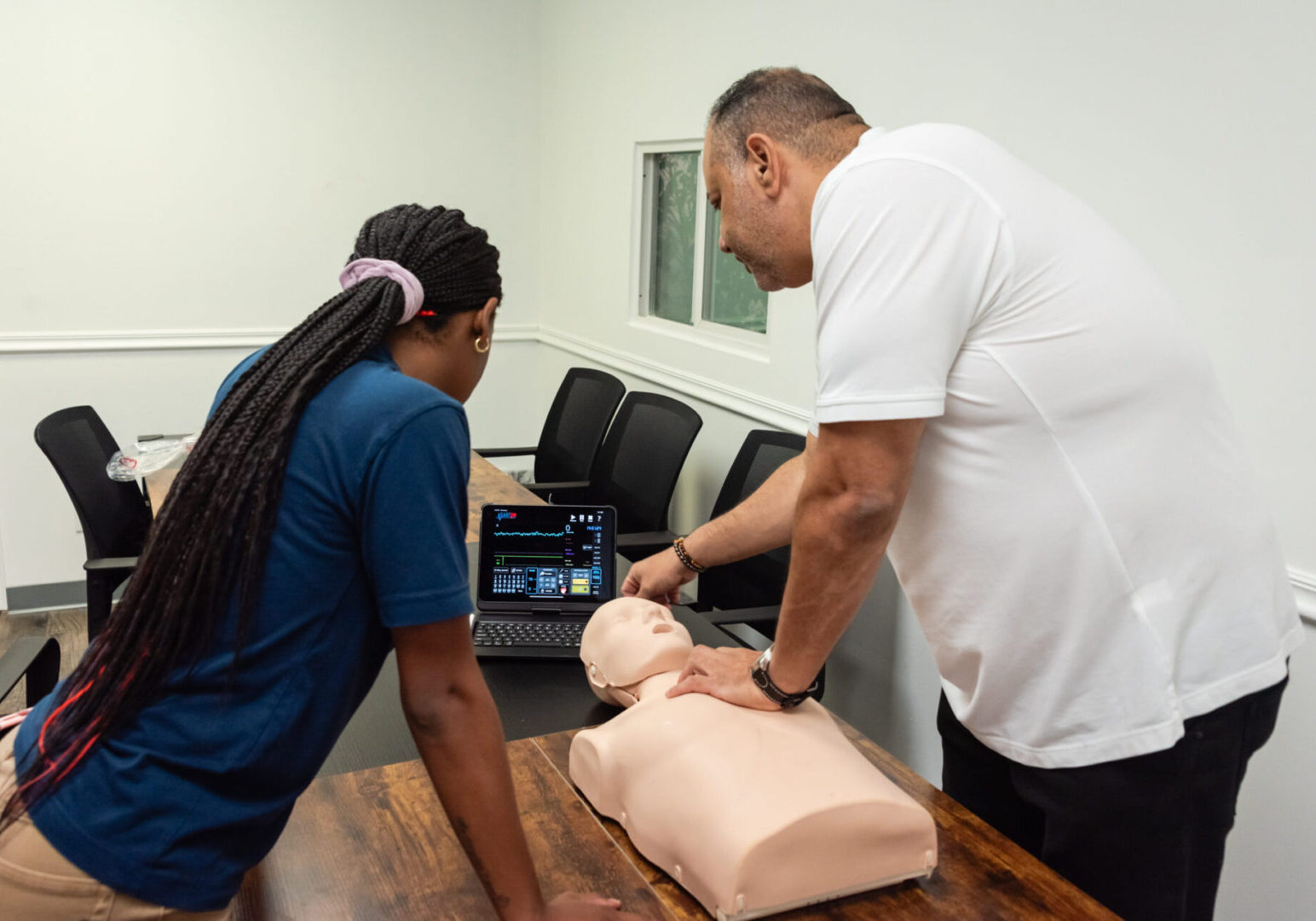 Two people practicing cpr on a dummy.