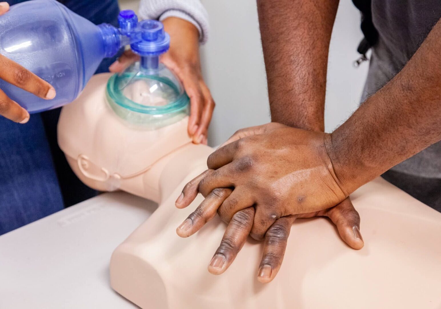 A person is performing cpr on an infant dummy.